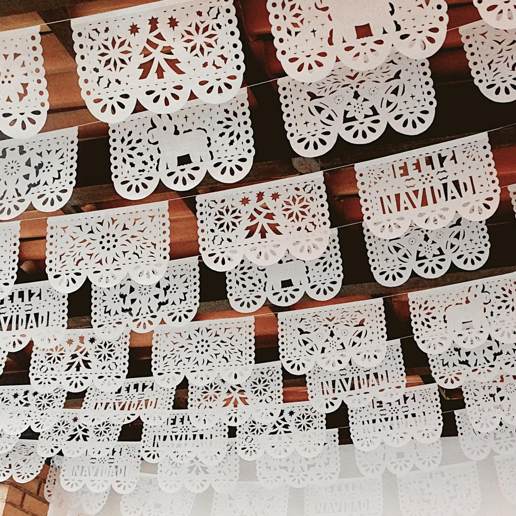 Decorative white christmas theme paper cutouts with intricate patterns on a wooden surface.