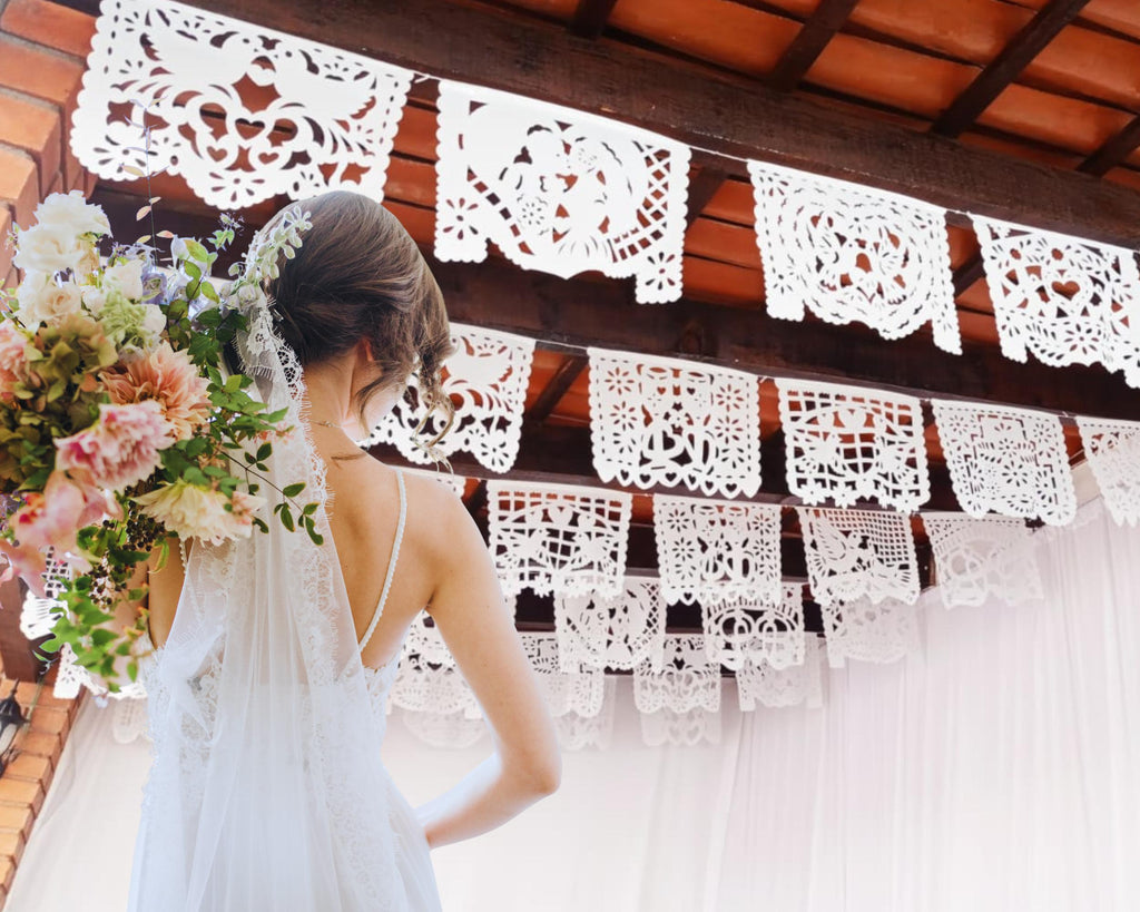 Bride holding a bouquet under decorative white lace banners.