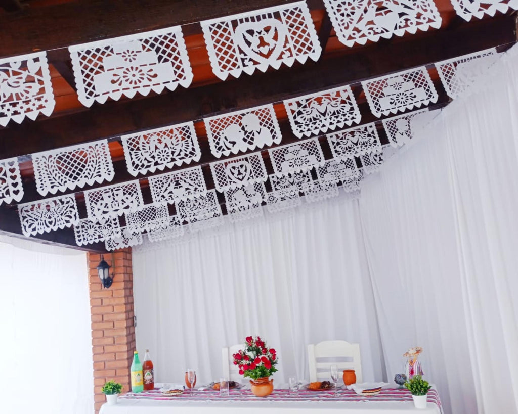 Decorative papel picado banner above a table with flowers