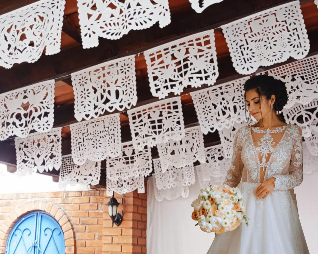 Woman in a wedding dress standing under decorative white paper cuttings.