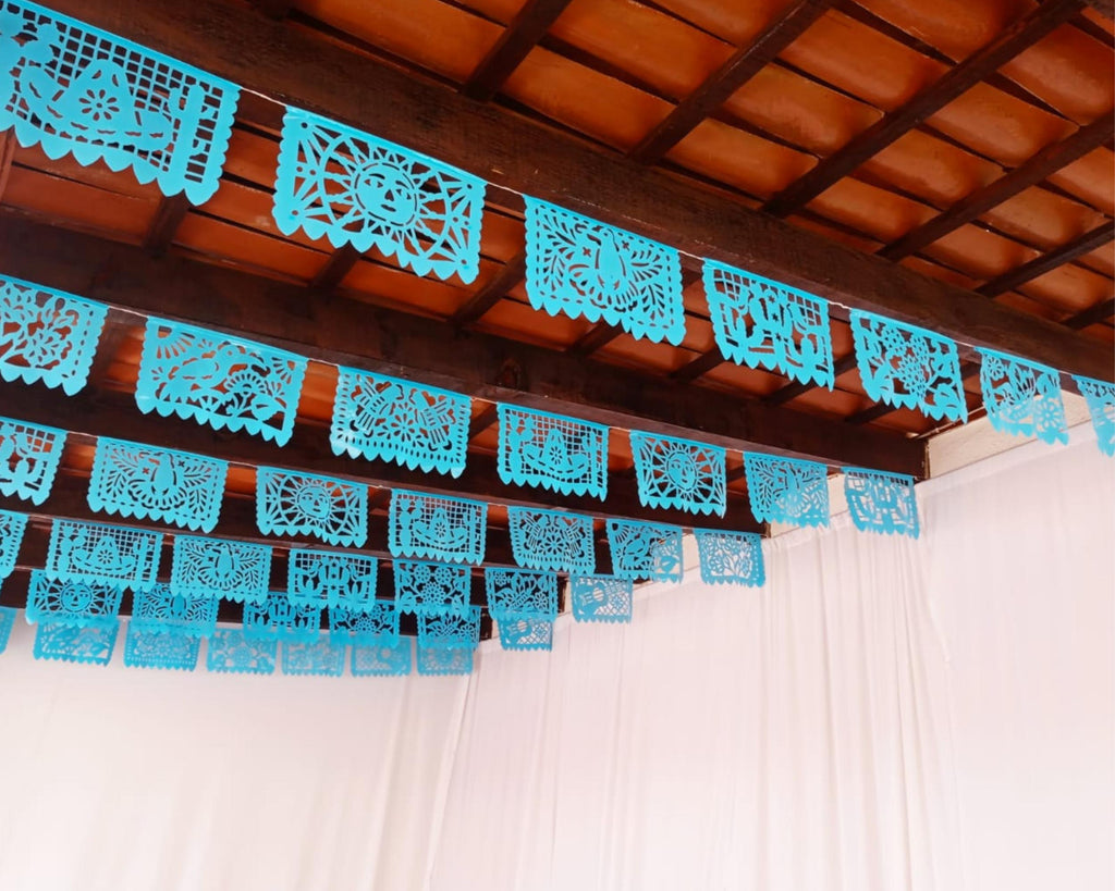 Turquoise blue papel picado hanging from a wooden ceiling