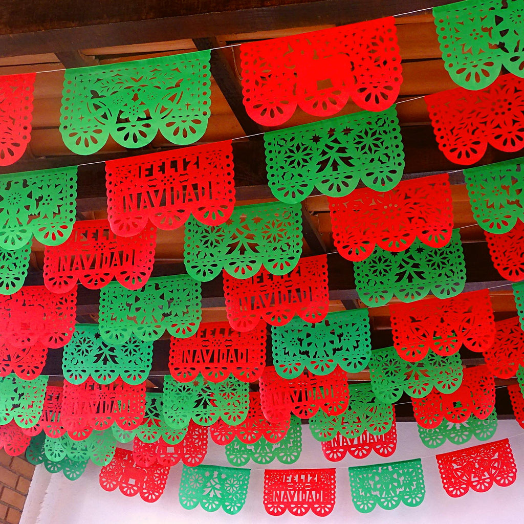 A series of green and red papel picado banners with decorative patterns and 'Feliz Navidad' text displayed for a Christmas celebration.